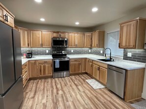 Una cucina moderna con mobili in legno, elettrodomestici in acciaio inossidabile e uno schienale rivestito di piastrelle grigie.