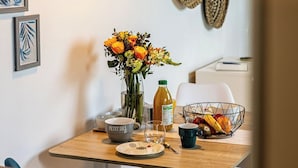A dining area with a wooden table, a vase of flowers, and a wall-mounted woven basket.