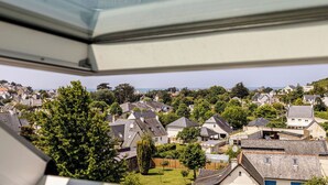 A residential area with houses, trees, and a clear view of the sea.