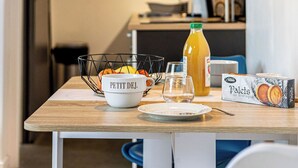 A dining table with a bowl, a bottle of orange juice, and a box of pastries.