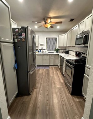 A modern kitchen with a refrigerator, microwave, stove, and ceiling fan. - 3-bedroom house in Delightful Del Rio, Texas with WiFi , AC. Come take a look. (Del Rio)