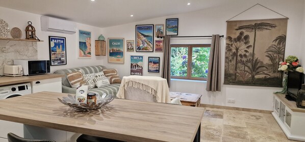 A cozy living area with a sofa, a coffee table, and a dining table. There are framed pictures on the wall and a large window with curtains. - At Stalla in the mountains near a stream (Ortiporio)