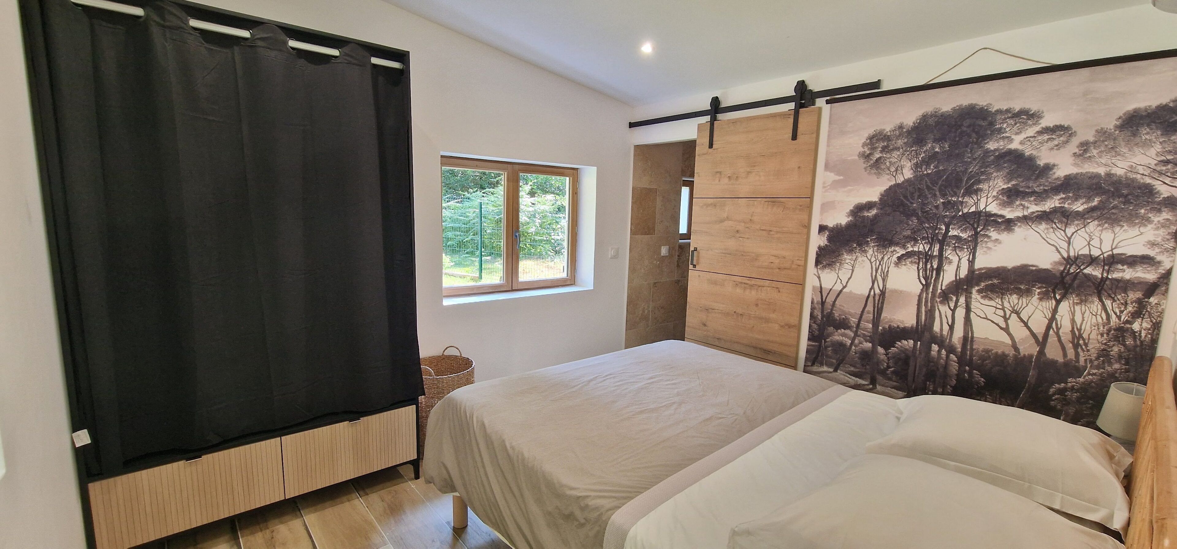 A bedroom with a bed, a window, a sliding door, and a painting.