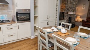 Una cocina moderna con armarios blancos, horno empotrado y chimenea de piedra.