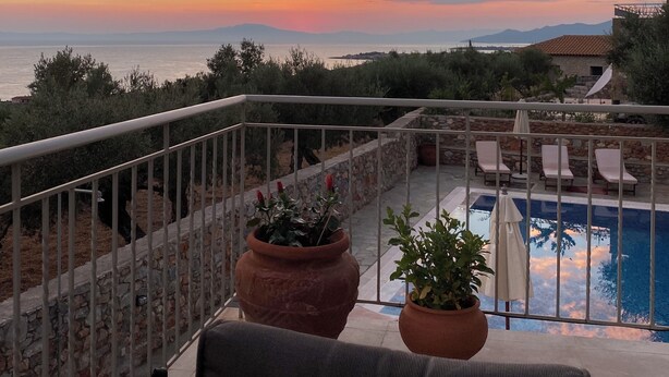 A balcony with a pool, potted plants, and a view of the sea at sunset. - Stunning Family sea view Villa with private pool (Stoupa)