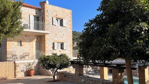 A stone building with a balcony, a pool, and potted plants. - Stunning Family sea view Villa with private pool (Stoupa)
