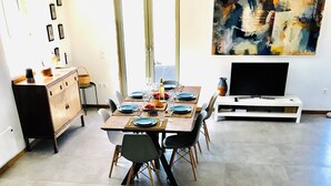 A dining area with a table set for four, a black stove in the foreground, and a painting on the wall. - Stunning Family sea view Villa with private pool (Stoupa)