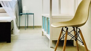 A minimalist room with a bed, a chair, a small table, and a wardrobe with a hanging rod. - Stunning Family sea view Villa with private pool (Stoupa)