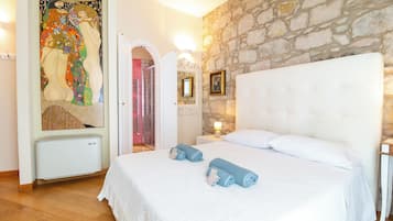 Ein Schlafzimmer mit einer Steinsandsteinwand, einem Bett mit weißen Leinen und einem großen Wandteppich.