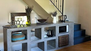 A modern kitchen with a grey island, built-in shelves, and a staircase. - Bosa Eye House 1873 (Bosa)