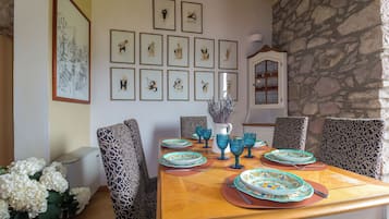 A dining area with a wooden table, patterned chairs, and framed artwork on the wall.