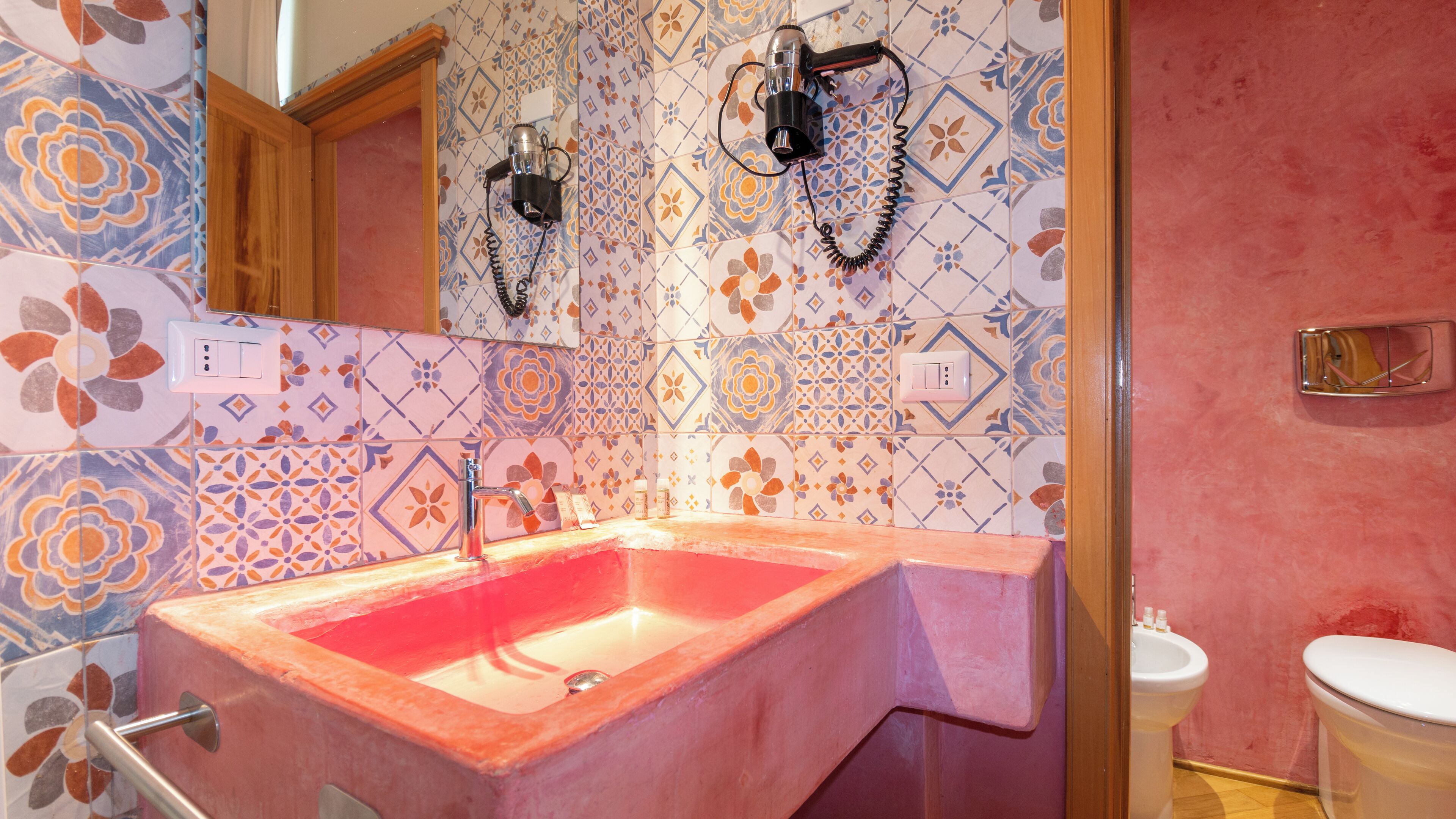 A bathroom with a pink sink, a mirror, and a shower area.