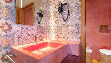 A bathroom with a pink sink, a mirror, and a shower area.