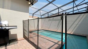 Zona piscina delimitata da una recinzione metallica, con una griglia barbecue e una visuale aperta sul cielo.