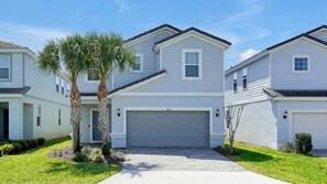 A residential building with a garage, a driveway, and a well-maintained lawn. - 7BR Solterra Villa | Private Pool & Spa | Mickey Room | Near Disney (Davenport)