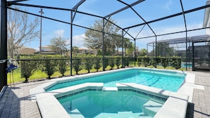 A swimming pool with a glass enclosure, surrounded by greenery and a clear sky. - 7BR Solterra Villa | Private Pool & Spa | Mickey Room | Near Disney (Davenport)