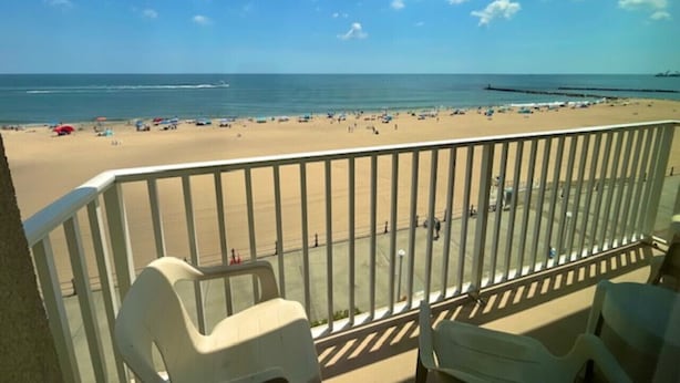 A balcony with a view of a beach, a sandy shore, and the ocean. - Beach House Oceanfront Condo | Indoor Pool Heated 606 (Virginia Beach)