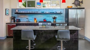 A modern kitchen with a central island, bar stools, a gas stove, and a stainless steel refrigerator. - Private Oceanfront Villa for 2 | Plunge Pool | St. John USVI (St. John)