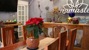A dining area with a wooden table, chairs, a vase with a plant, and a wall with a sign. - Loft & Terrace Central, Safe, Condesa/Roma/WTC, kitchenette, Hi-Wifi, Get to know us (Ciudad de México)