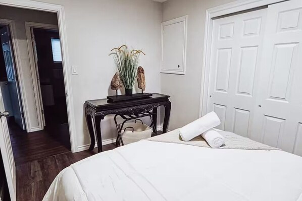 A bedroom with a bed, a nightstand, a potted plant, and a door. - Spacious 3BR Retreat, Firepit & Outdoor Kitchen – Walk to Falls (Niagara Falls)