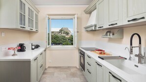 A modern kitchen with a view of a historic building through a window. - Nafsika's Grande Residence in Corfu Town (Corfu)