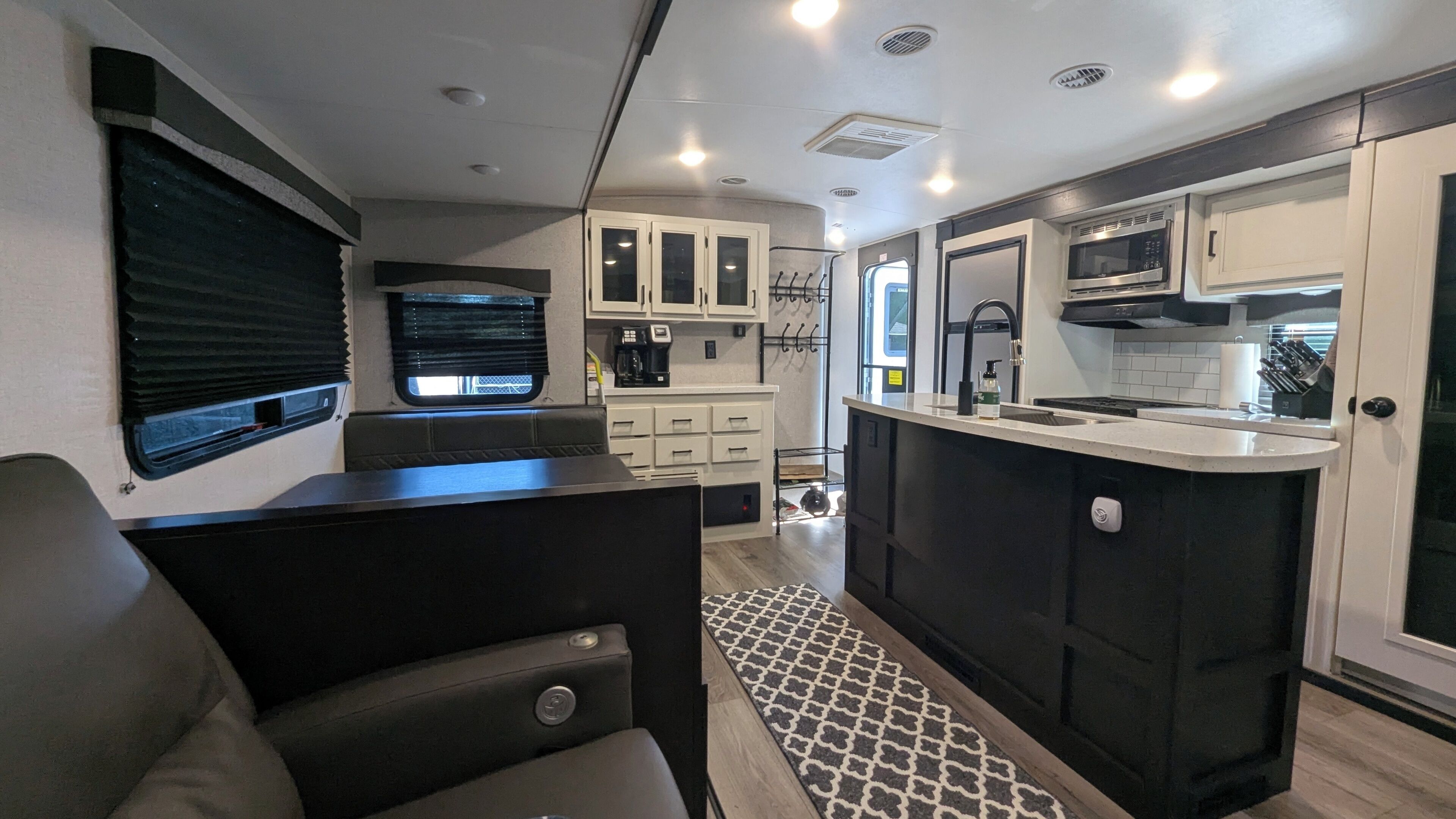 Interior compacto de una caravana, con kitchenette, zona de estar y una ventana pequeña.