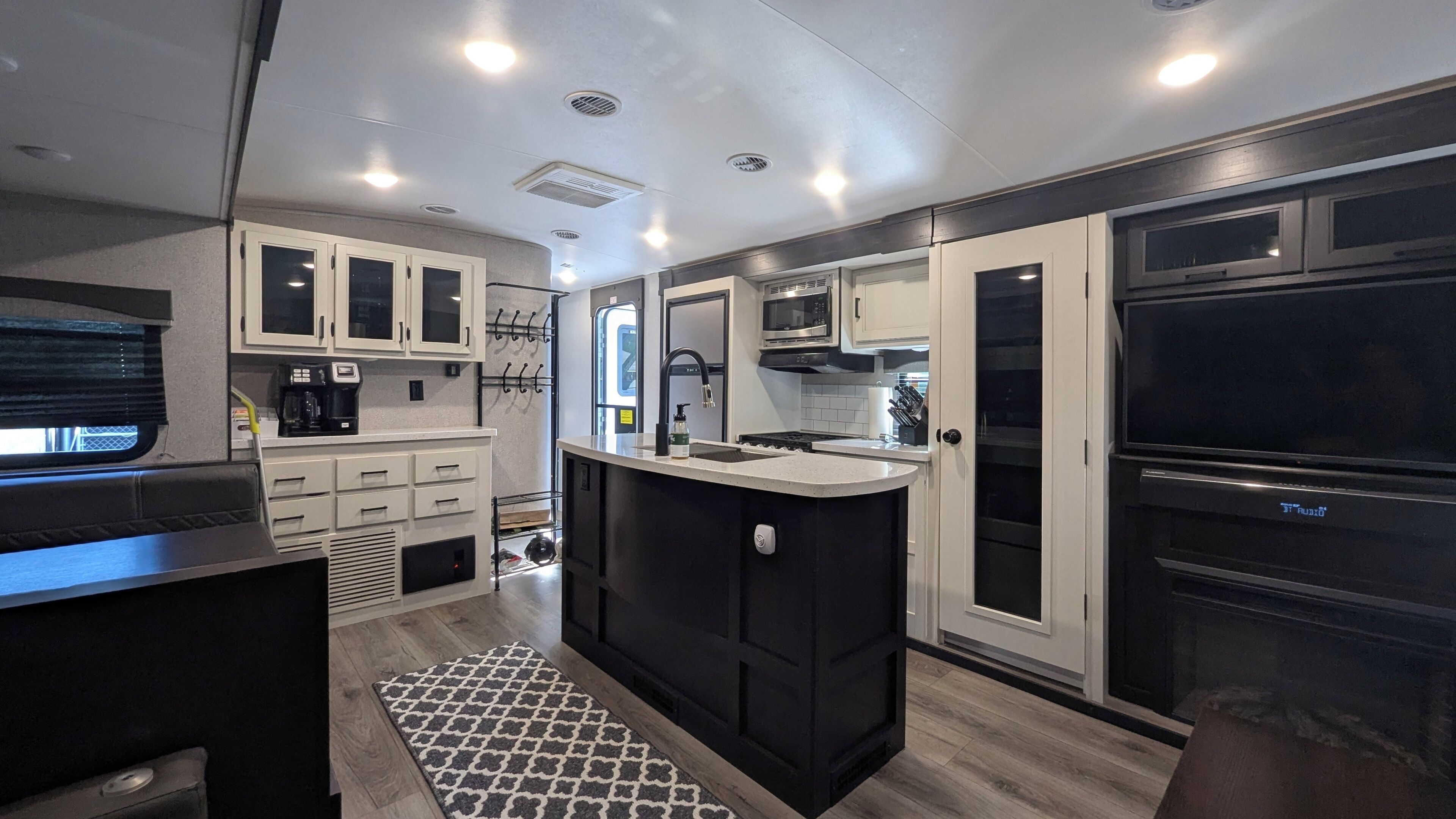 A modern kitchen with a central island, built-in appliances, and a dining area with a bench.