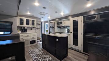 A modern kitchen with a central island, built-in appliances, and a dining area with a bench.
