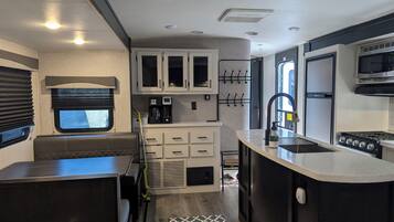 Een compacte camperkeuken met een kitchenette, een spoelbak, een fornuis en een raam.