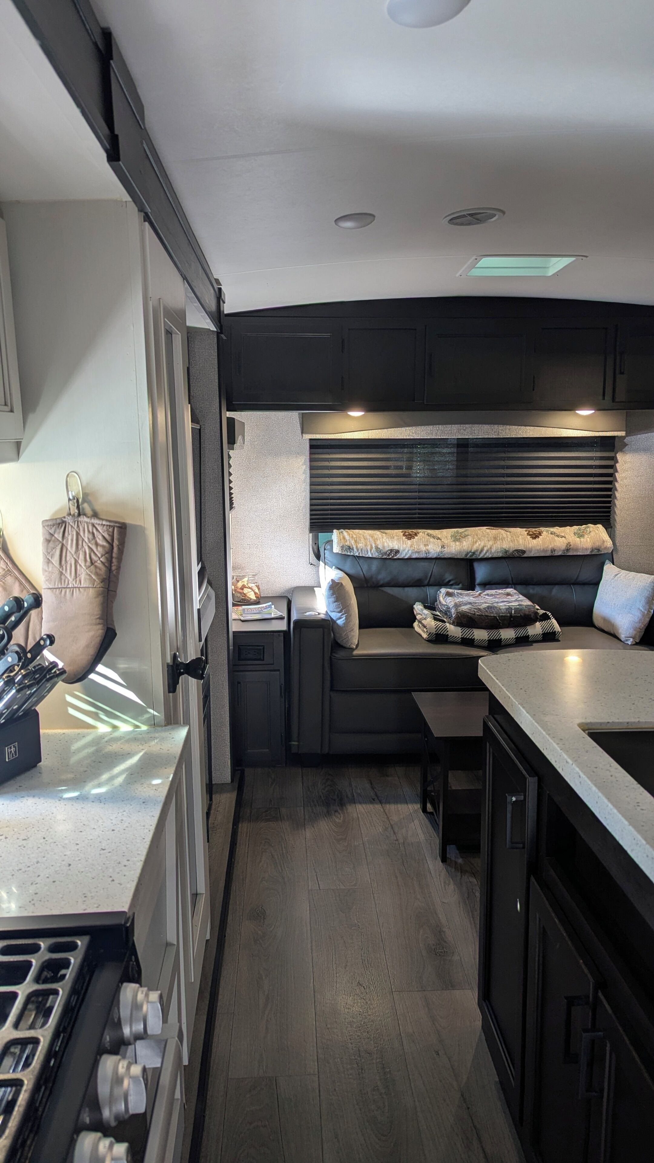 Cocina compacta con estufa integrada, muebles oscuros y un rincón de estar con cojines.