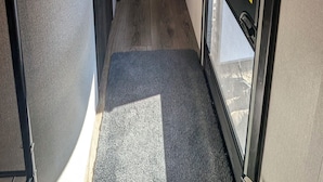 Un couloir étroit avec un lit, une porte et une fenêtre.