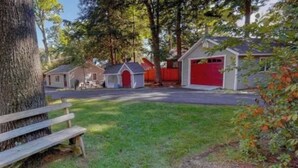 A residential area with a red garage, a small shed, and a wooden bench. - Elevate your Escape (Lake George)