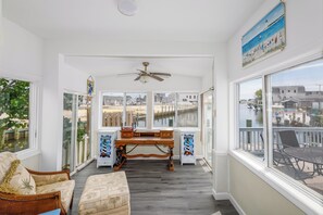 A sunlit room with a wooden desk, a cushioned bench, and a view of a dock and water. - Serenity and Water fun abound in. this 3+ Bedroom on the Lagoon in Bayville! (Berkeley Township)