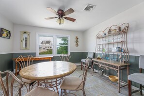 A dining area with a round table, chairs, a ceiling fan, and a metal shelf with glassware. - Serenity and Water fun abound in. this 3+ Bedroom on the Lagoon in Bayville! (Berkeley Township)