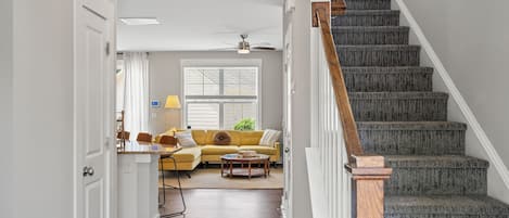 Stairs lead to a second floor living area with a sofa and coffee table.