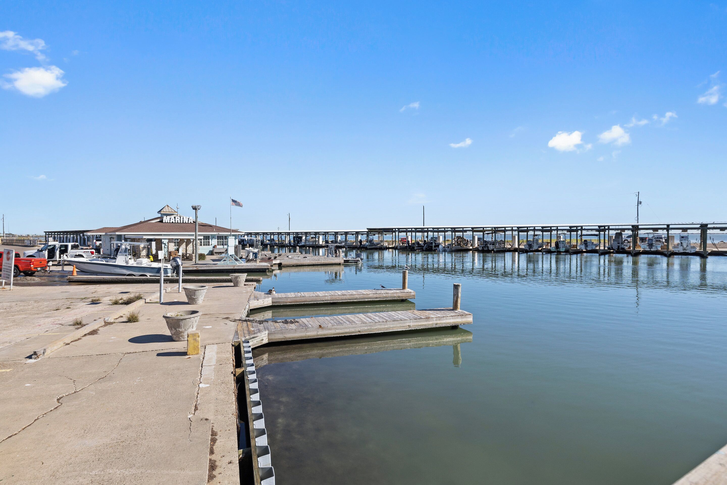 Un puerto deportivo con barcos amarrados, una zona de espera techada y un muelle que se adentra en aguas tranquilas.