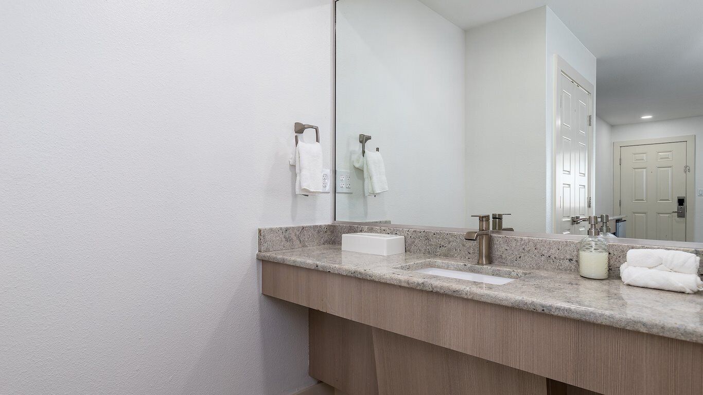 Une salle de bain moderne avec un comptoir en granit, un double vasque et un grand miroir.