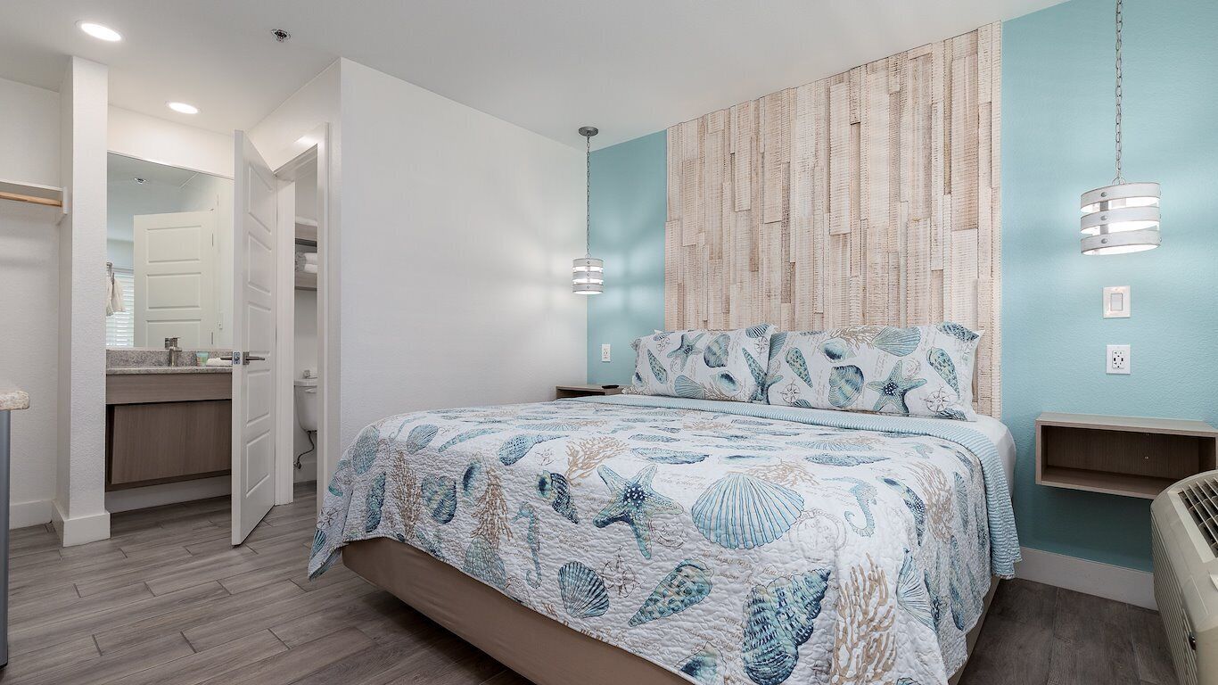 Un dormitorio con cama, mesita de noche, estante en la pared y lámpara colgante.