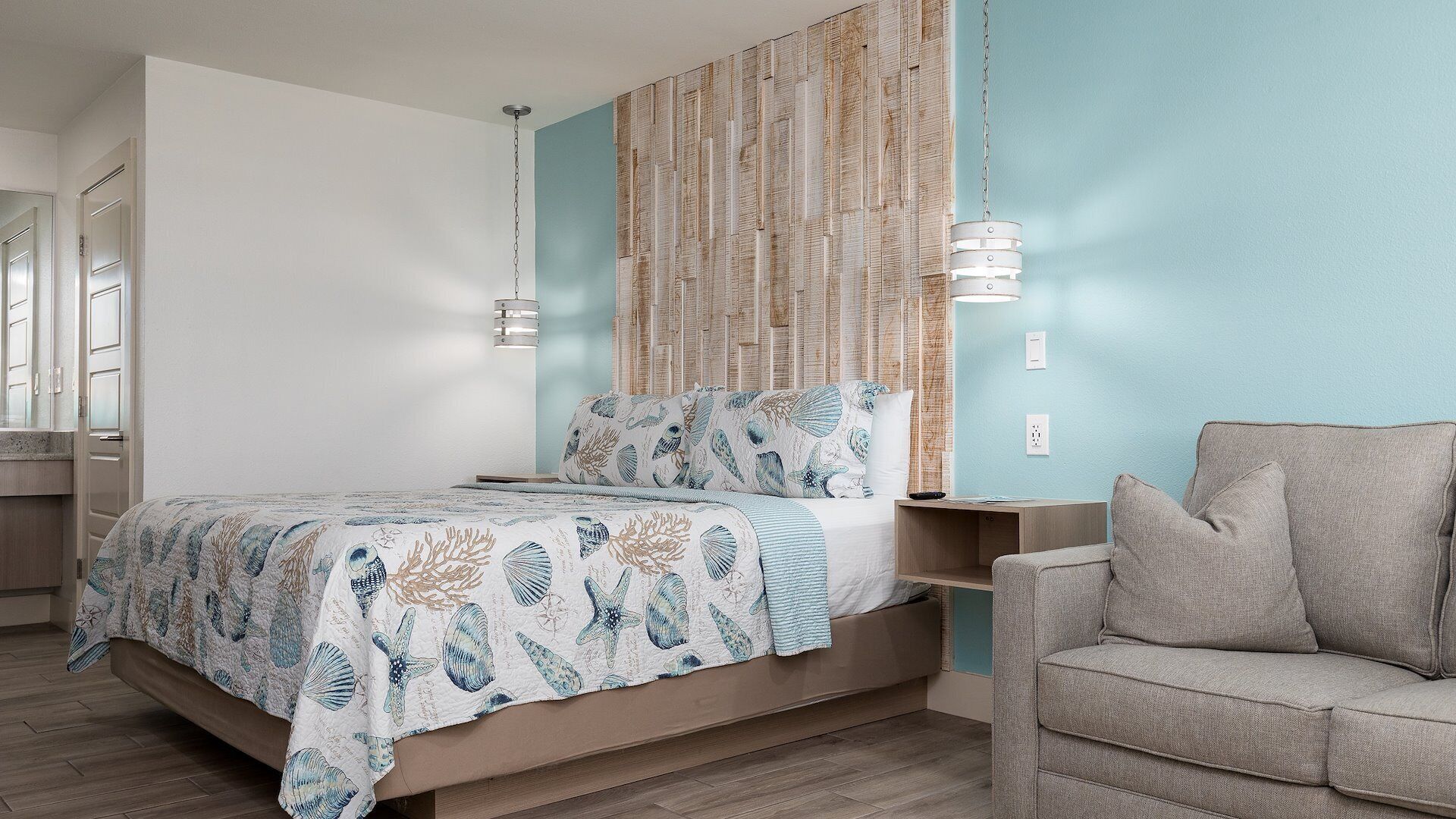 A bedroom with a bed, a nightstand, a chair, and a wall with a textured pattern.