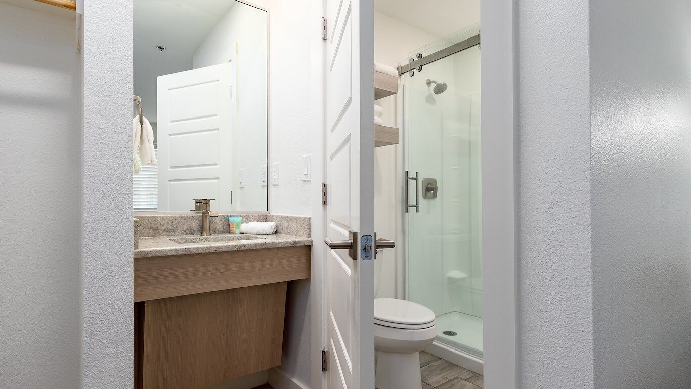 A modern bathroom with a glass shower enclosure, a white toilet, and a wooden vanity with a countertop.