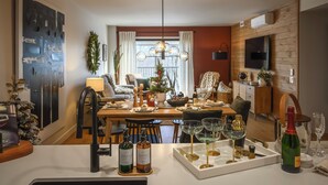 A dining area with a wooden table set for a meal, a chandelier, and a television mounted on the wall.