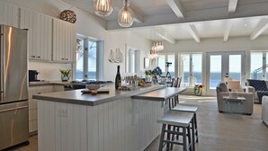 Una cocina moderna con una isla grande, armarios blancos y vistas al océano.