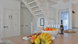 Una cocina con una isla de madera, armarios blancos y una escalera blanca, con vistas al exterior.