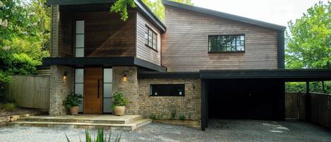 A modern two-story house with a stone facade, a wooden upper level, and a garage.
