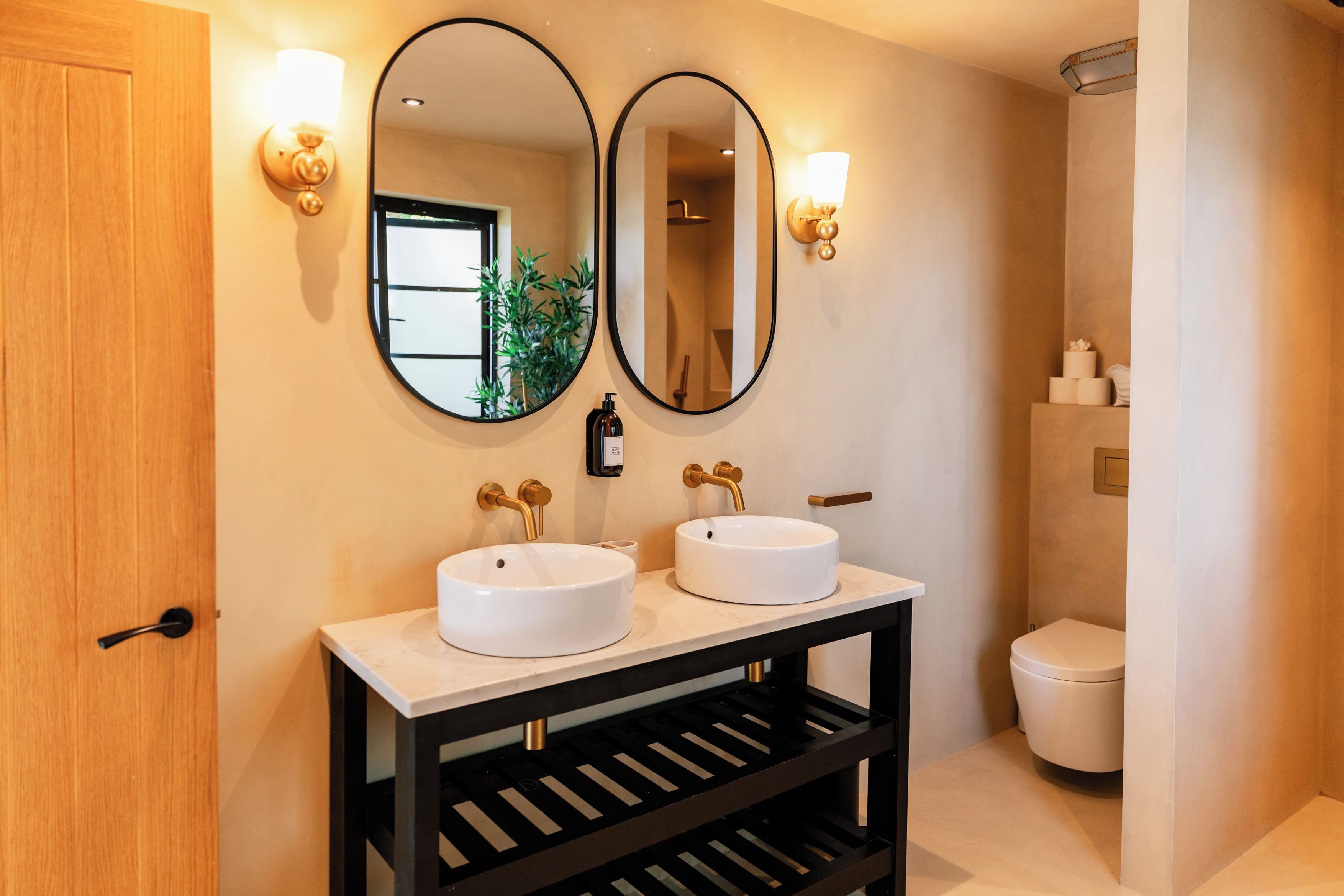 A bathroom with two sinks, a mirror, and a toilet.