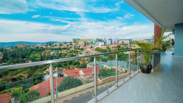 Varanda com grade de metal, vista para um horizonte urbano com edifícios e áreas verdes.