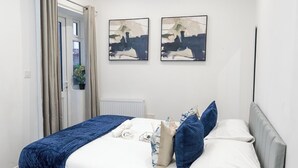 A bedroom with a bed, pillows, a blue blanket, and two abstract paintings on the wall.