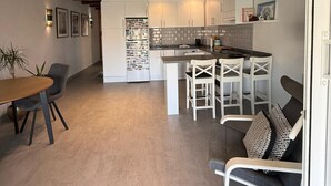 Eine moderne Küche mit weißen Schränken, einer zentralen Kochinsel und einem Essbereich mit Tisch und Stühlen.