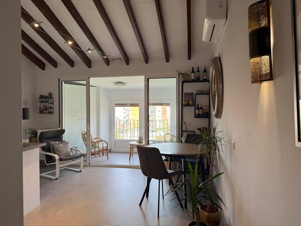 Un vaste espace de vie comprenant une table à manger, des chaises et un canapé. Une grande fenêtre offre une vue sur l’extérieur.
