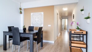 A modern dining area with a dark wooden table and chairs, a decorative wall piece, and a hallway leading to another room.
